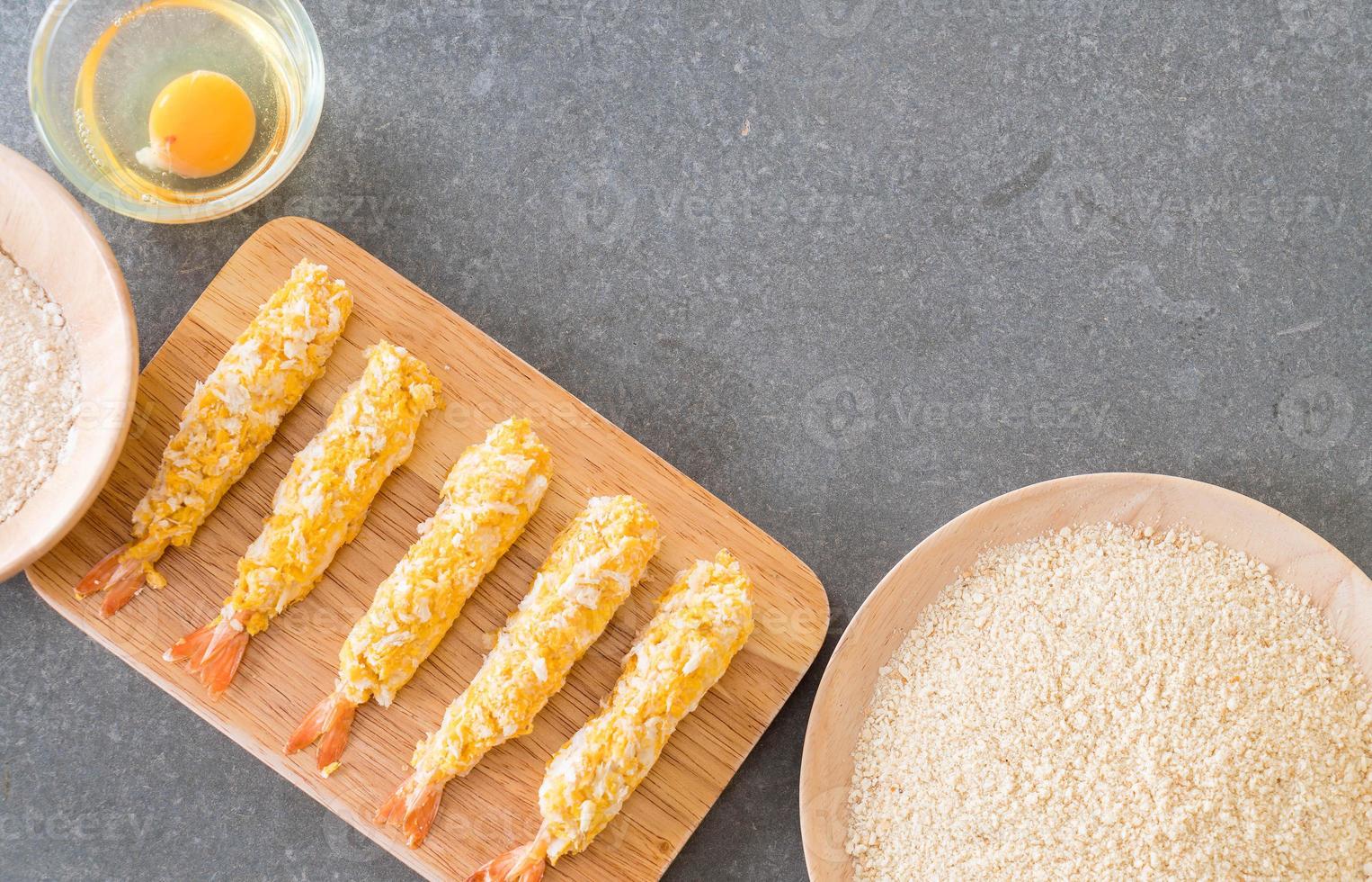 Camarões fritos em massa na tábua de madeira com ingredientes foto