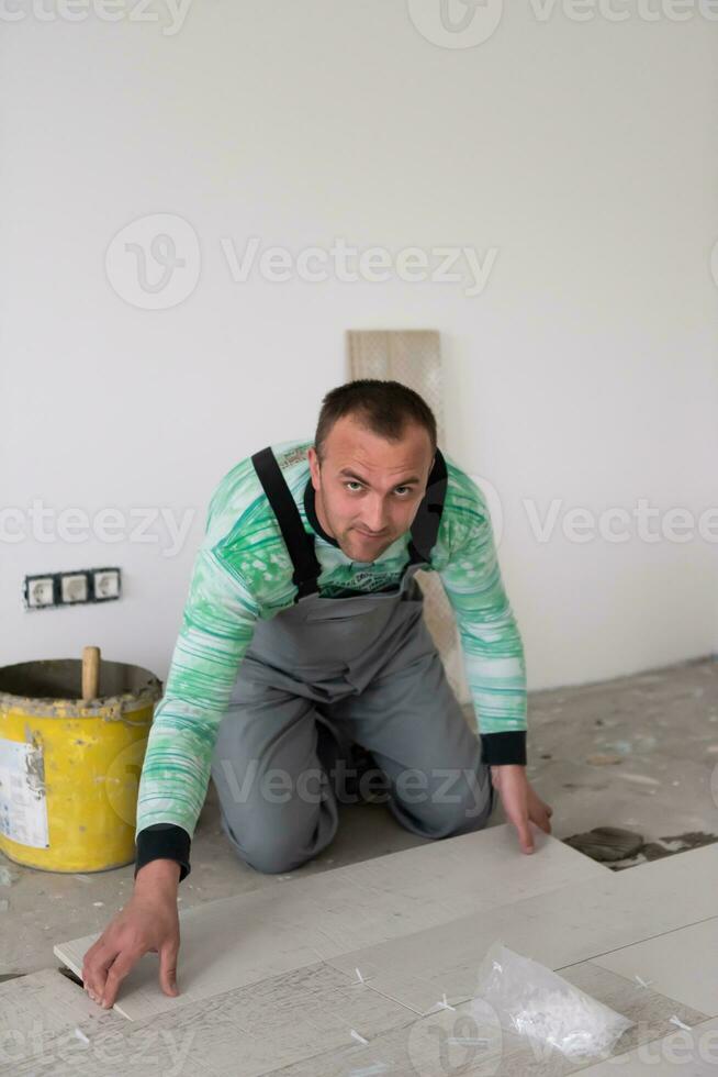 trabalhador instalando as telhas cerâmicas de efeito de madeira no chão foto