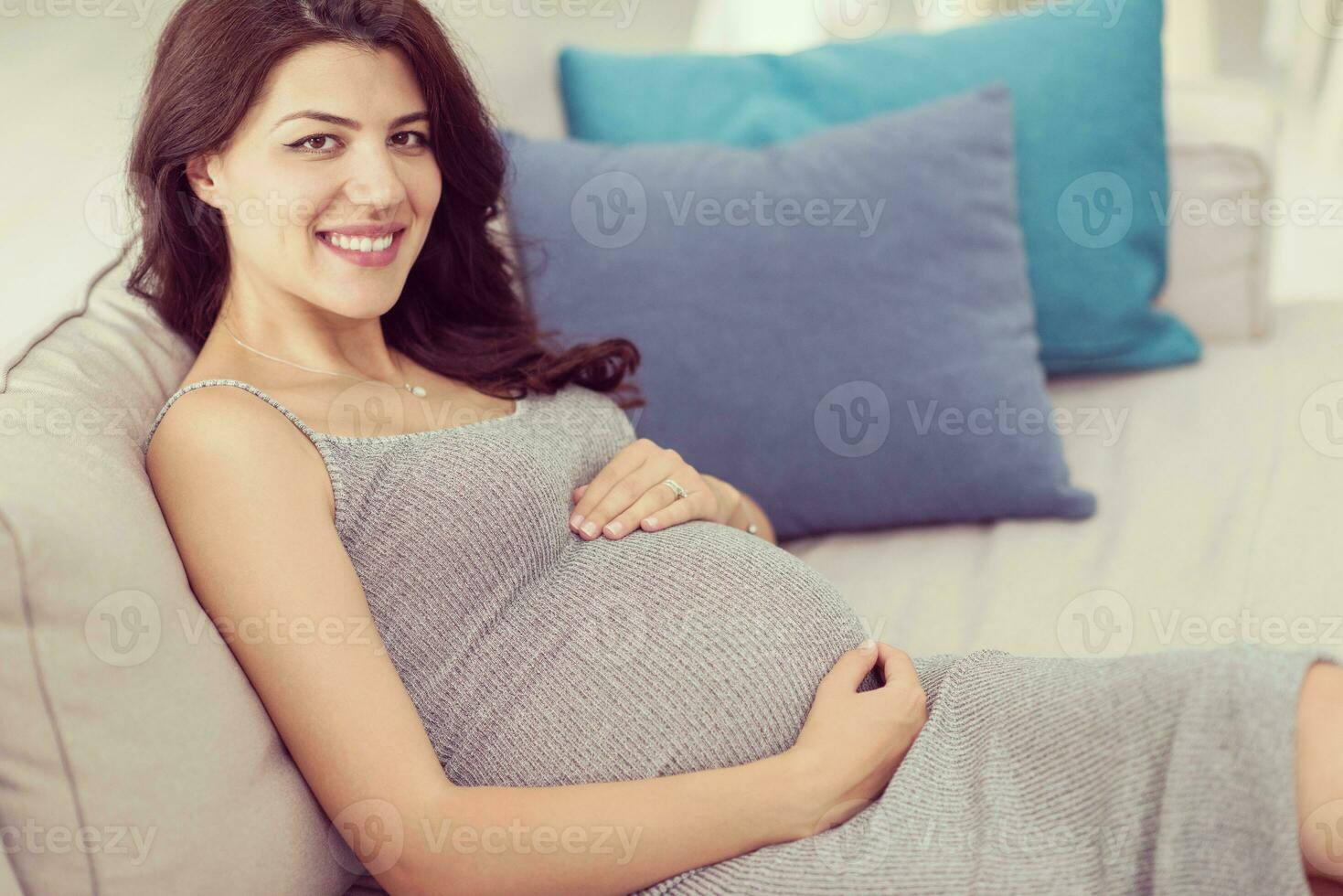 mulher grávida sentada no sofá em casa foto