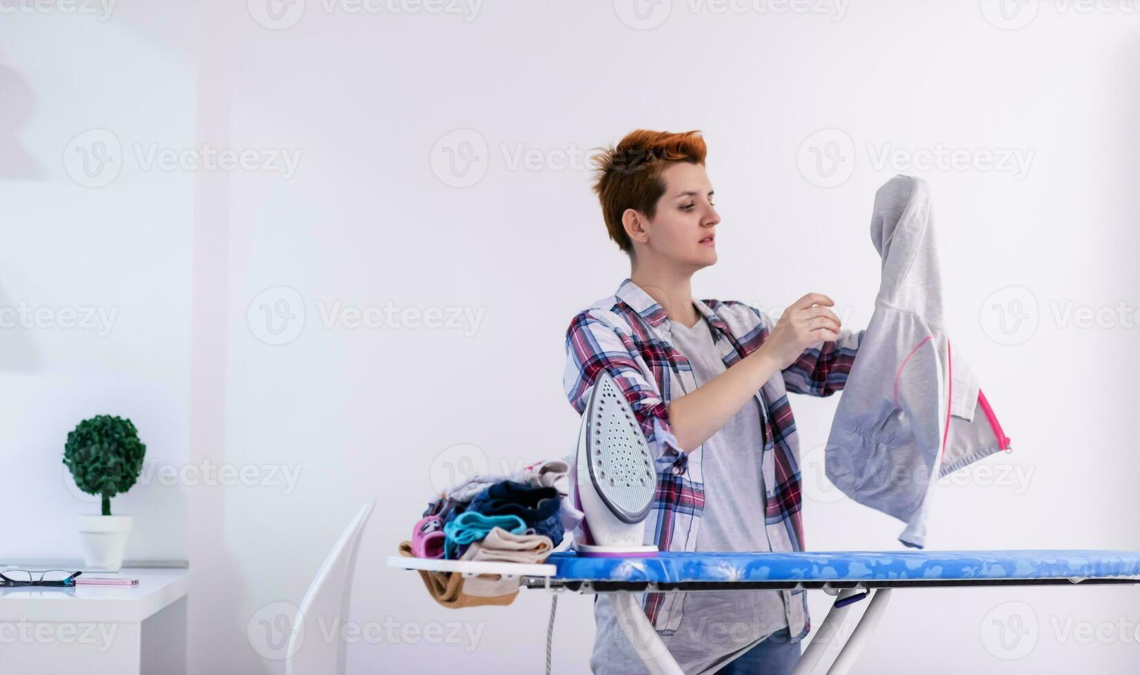 mulher ruiva passando roupa em casa foto