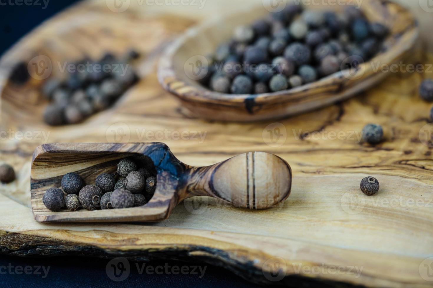 algumas bolas de pimenta da Jamaica em madeira de oliveira foto