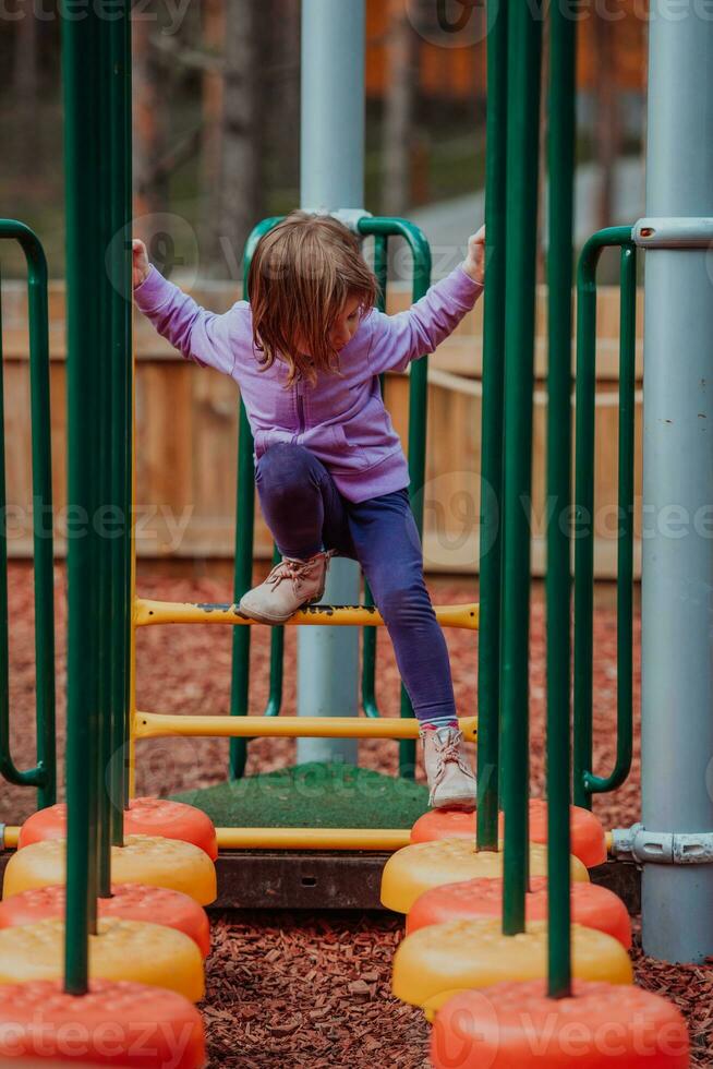 uma pequeno menina jogando dentro a parque. a conceito do família socializar dentro a parque. uma menina balanços em uma balanço, tocam criativo jogos foto