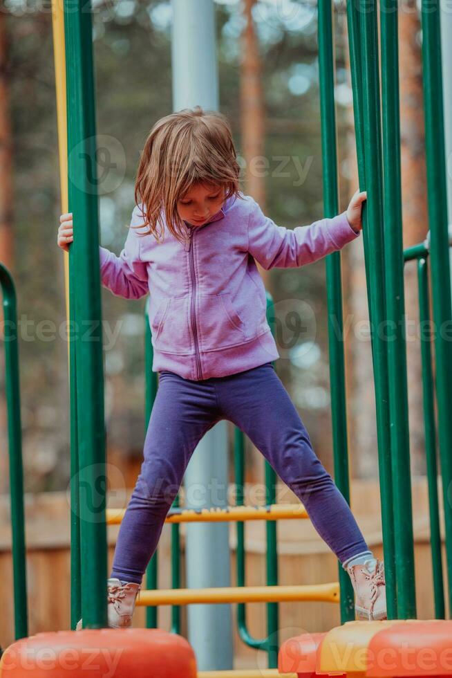 uma pequeno menina jogando dentro a parque. a conceito do família socializar dentro a parque. uma menina balanços em uma balanço, tocam criativo jogos foto