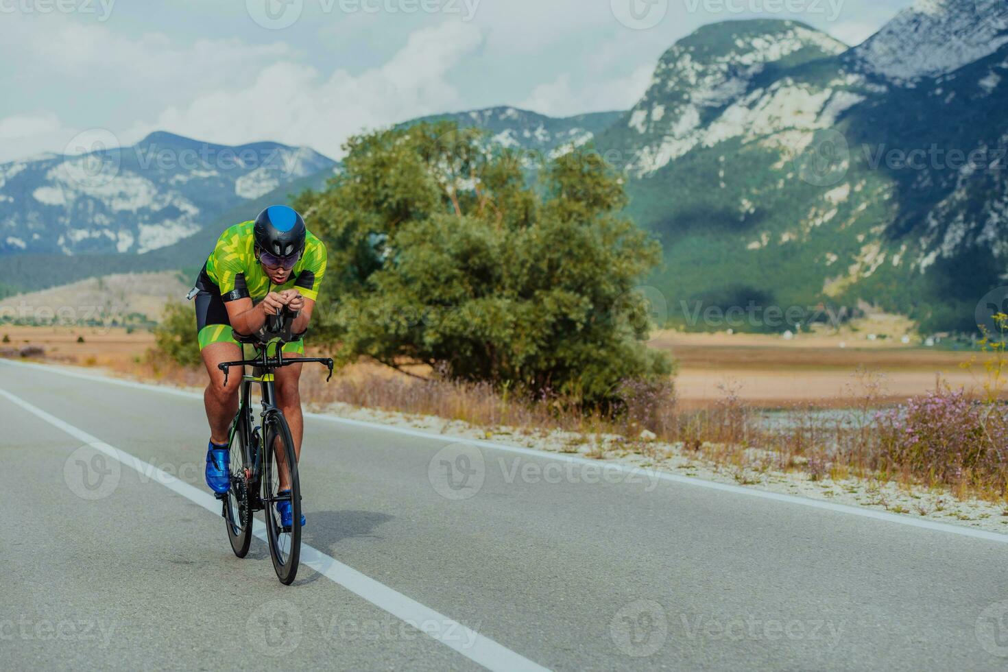 cheio comprimento retrato do a ativo triatleta dentro roupa de esporte e com uma protetora capacete equitação uma bicicleta. seletivo foco foto