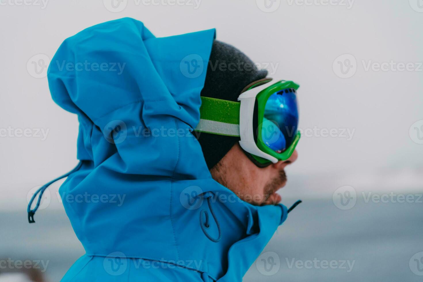 Tiros na Cabeça foto do uma homem dentro uma frio Nevado área vestindo uma Grosso azul inverno jaqueta, neve óculos e luvas. vida dentro frio regiões do a país.