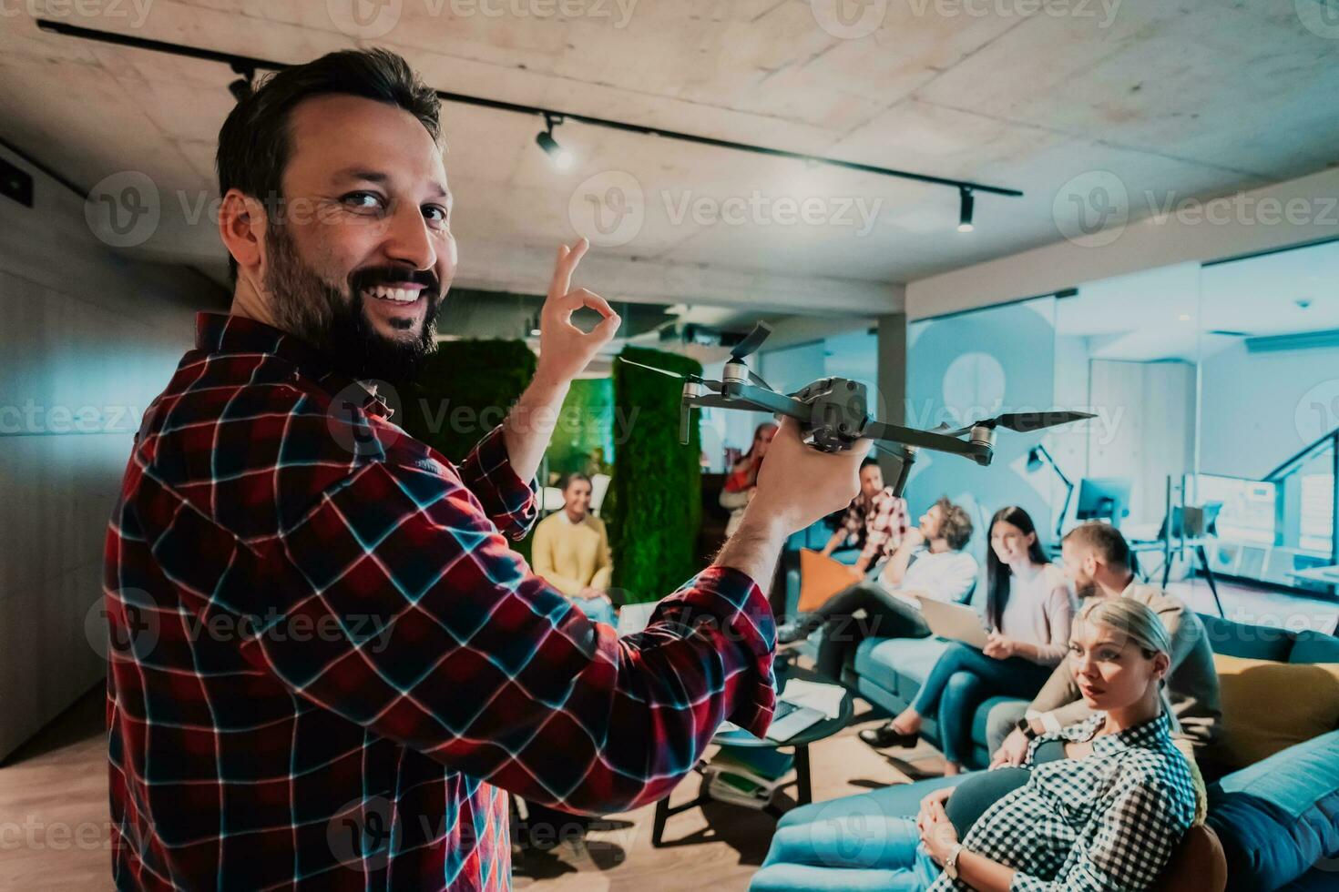 uma barbudo homem dentro uma moderno escritório explicando para dele jovem diverso equipe quão uma zangão trabalhando foto