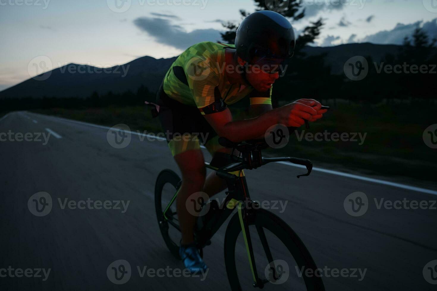 atleta de triatlo andando de bicicleta à noite foto