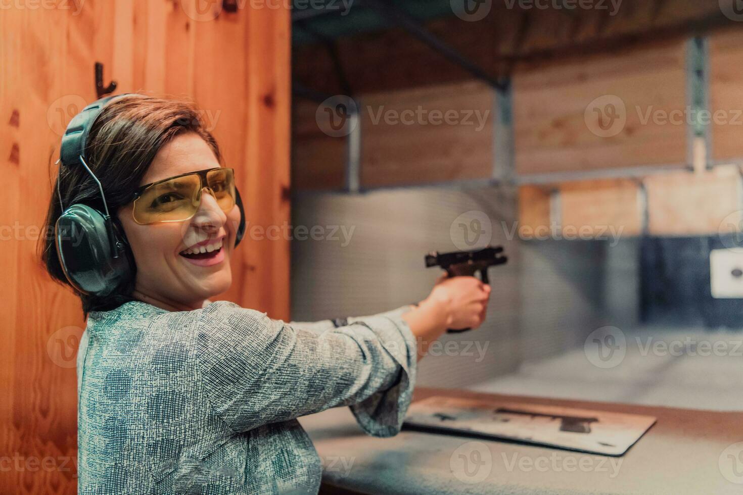 uma mulher práticas tiroteio uma pistola dentro uma tiroteio alcance enquanto vestindo protetora fones de ouvido foto