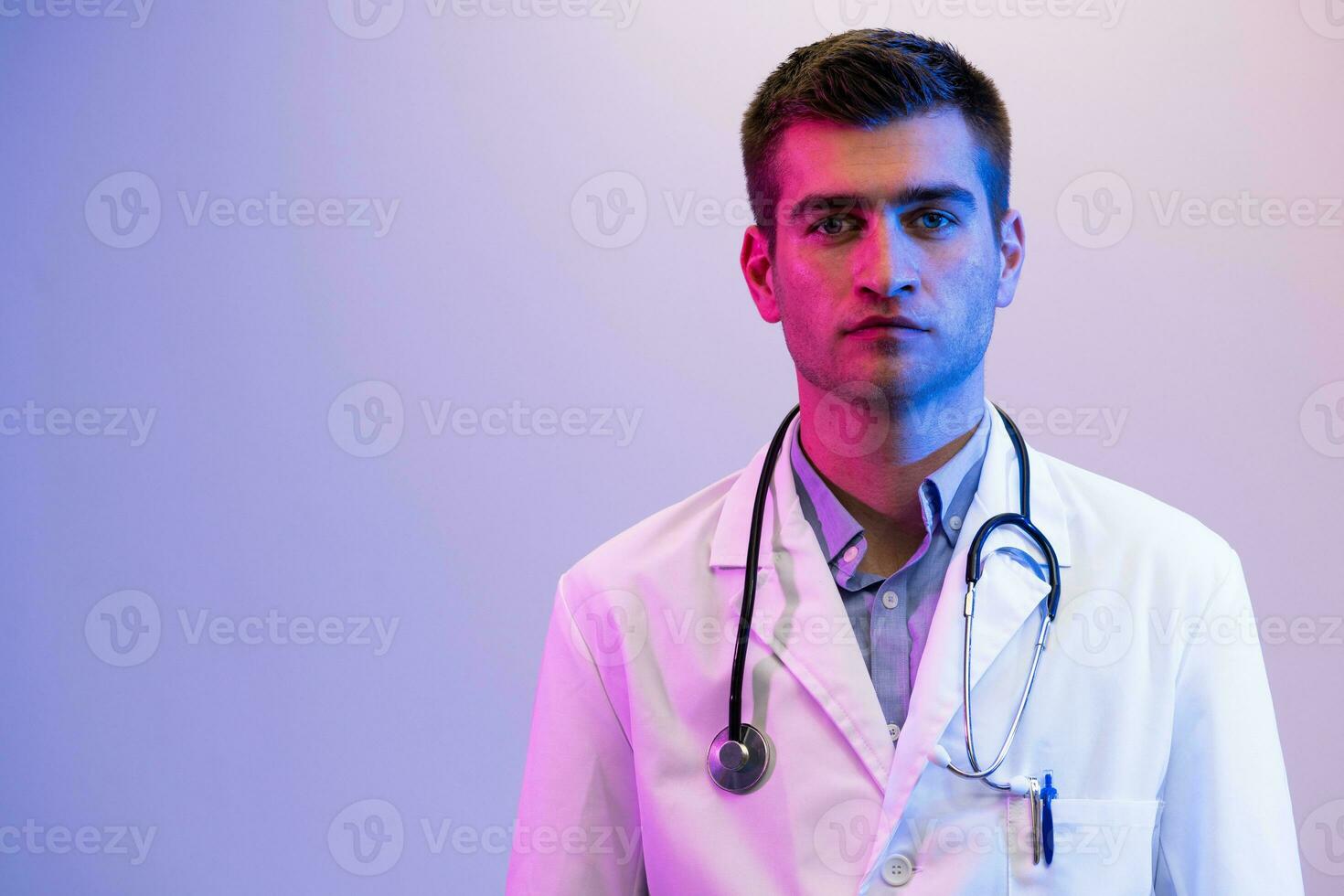 coronavírus covid-19 Perigo alerta retrato do herói dentro branco casaco. alegre sorridente jovem médico com estetoscópio dentro médico hospital em pé contra azul e Rosa fundo. foto