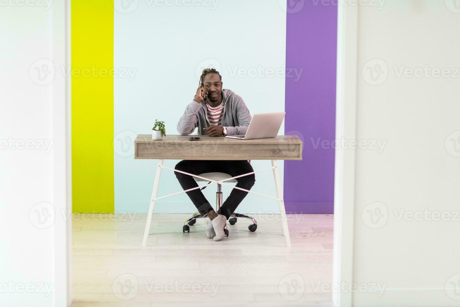 sorridente jovem africano homem trabalhador autonomo usando computador portátil e Smartphone estudando conectados trabalhando a partir de casa foto