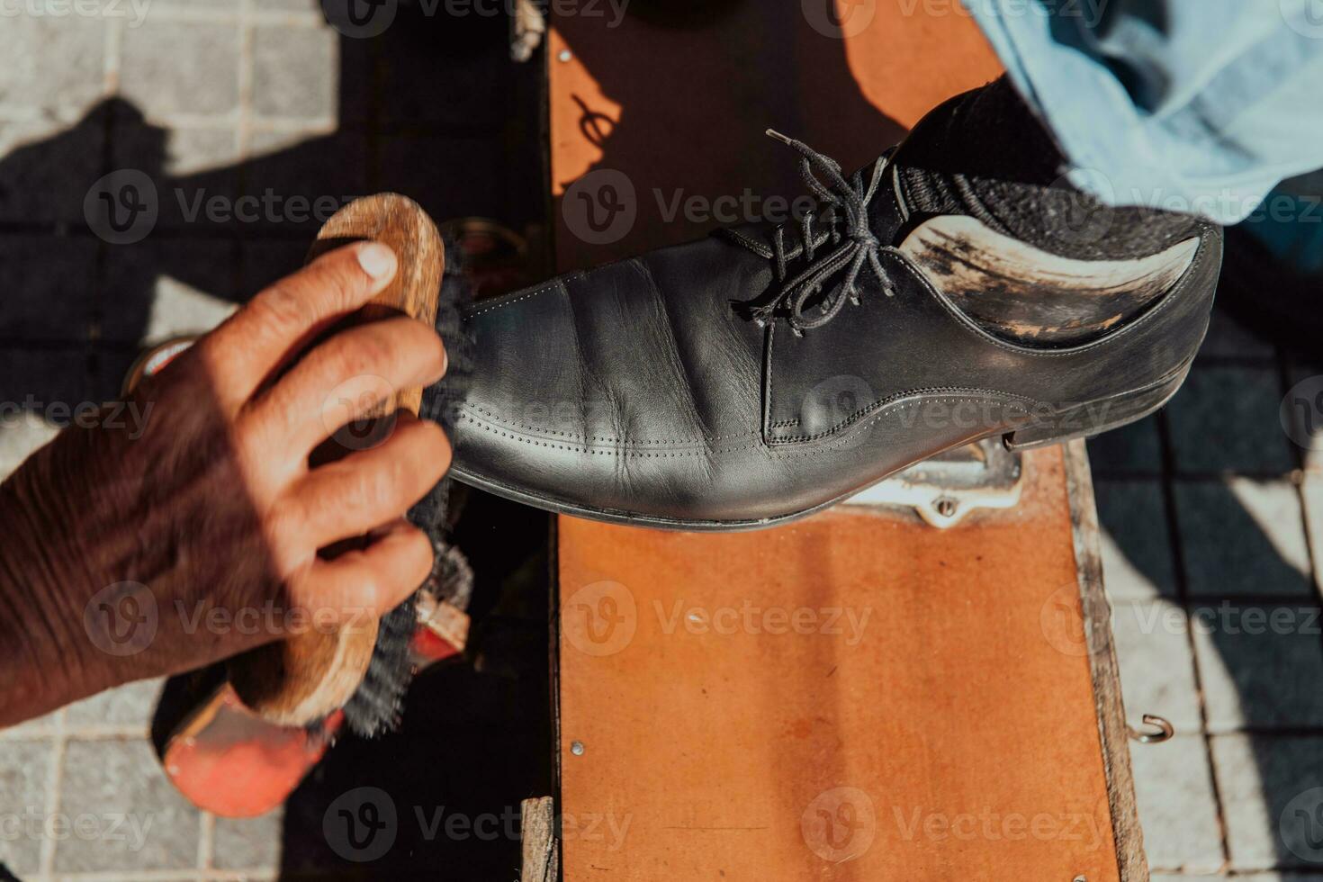 a velho homem mão polimento e pintura uma Preto sapato às rua foto