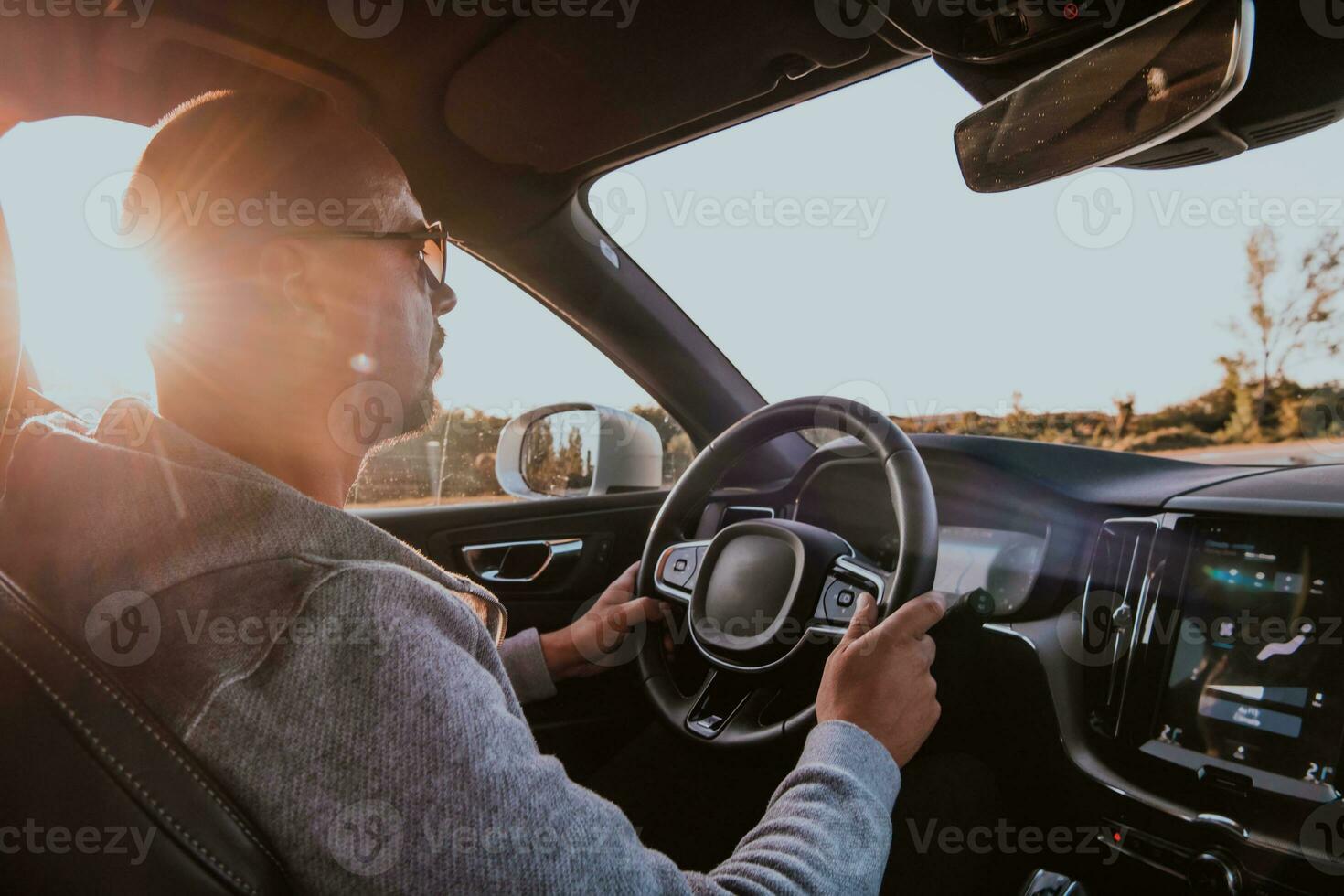 uma homem com uma oculos de sol dirigindo uma carro às pôr do sol. a conceito do carro viagem foto