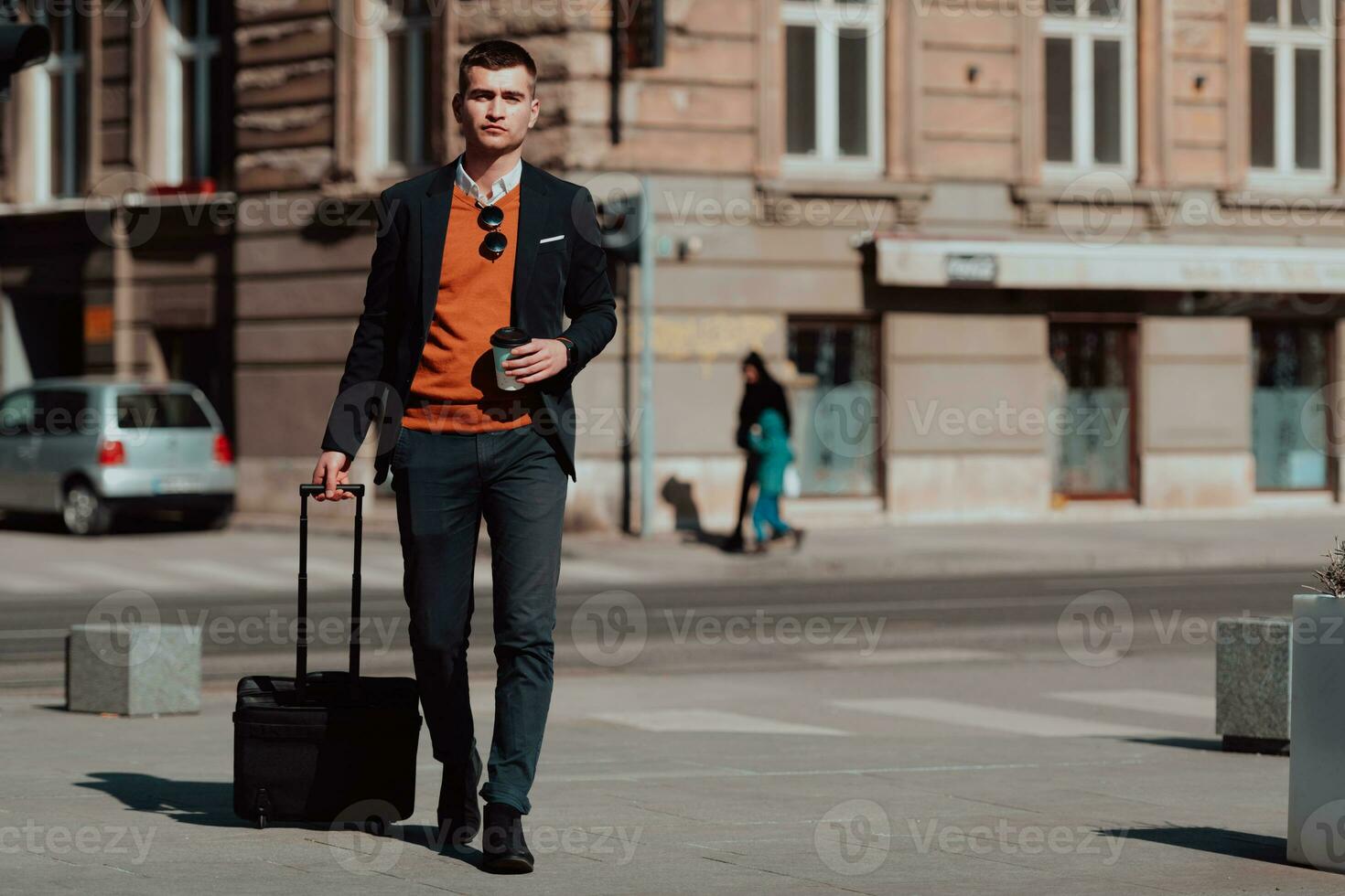 indo para o terminal do aeroporto. viajante empresário confiante andando nas ruas da cidade e puxando sua mala tomando café e falando no smartphone foto