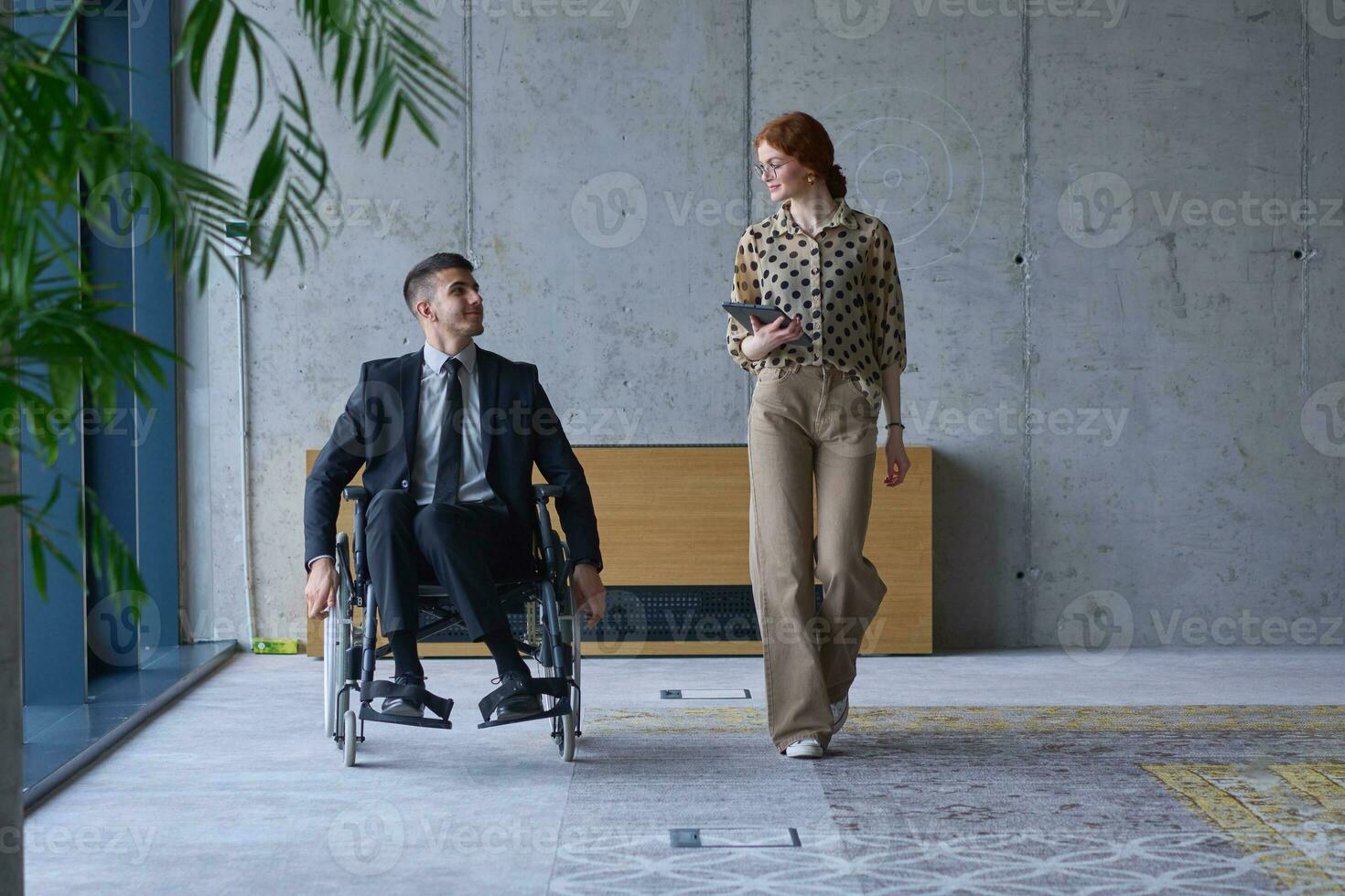 uma homem de negocios dentro uma cadeira de rodas e dele fêmea colega juntos dentro uma moderno escritório, representando a poder do trabalho em equipe, inclusão e apoiar, fomento uma dinâmico e inclusivo trabalhos ambiente. foto