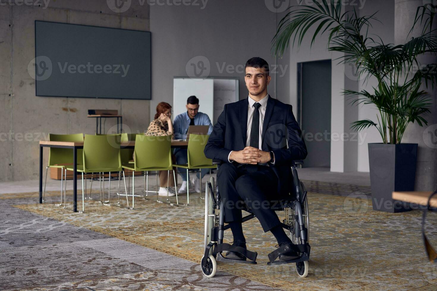 homem de negocios dentro uma cadeira de rodas comandos atenção, simbolizando resiliência e sucesso no meio uma dinâmico moderno escritório ambiente. foto