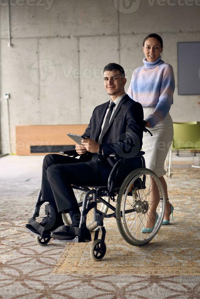 uma homem de negocios dentro uma cadeira de rodas e dele fêmea colega juntos dentro uma moderno escritório, representando a poder do trabalho em equipe, inclusão e apoiar, fomento uma dinâmico e inclusivo trabalhos ambiente. foto