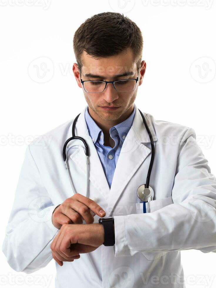 médico dentro terno com estetoscópio usando inteligente Assistir enquanto isolado em branco fundo foto