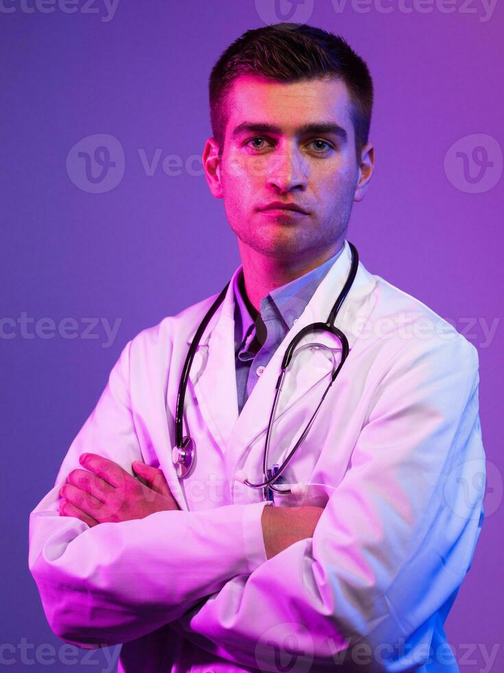 retrato do herói dentro branco casaco. alegre sorridente jovem médico com estetoscópio dentro médico hospital em pé contra azul e Rosa fundo. coronavírus covid-19 Perigo alerta foto