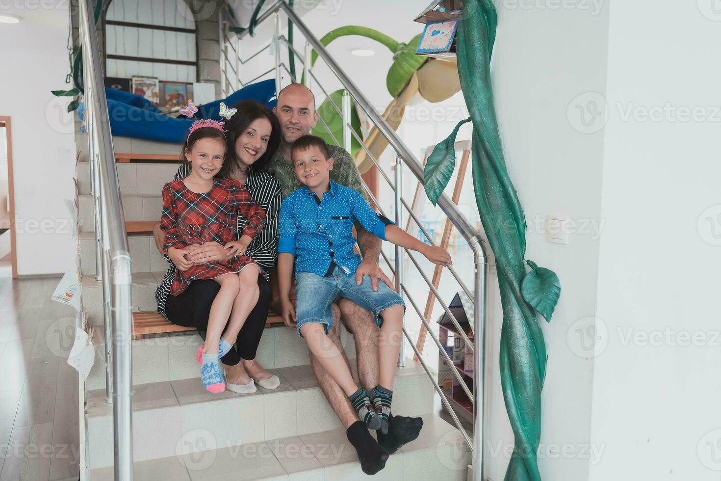 retrato do uma feliz família. foto do pais com crianças dentro uma moderno pré escola sala de aula. seletivo foco