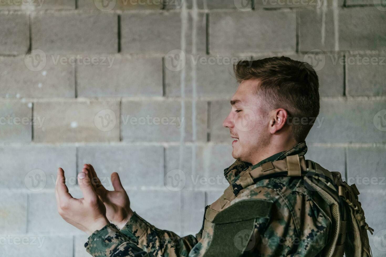 uma muçulmano soldado do a especial forças ora para Deus de levantando dele mãos e começa uma oração foto