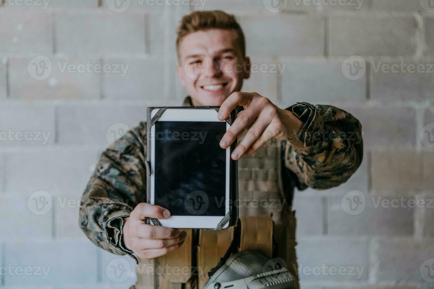 soldado usando tábua computador contra velho tijolo parede foto