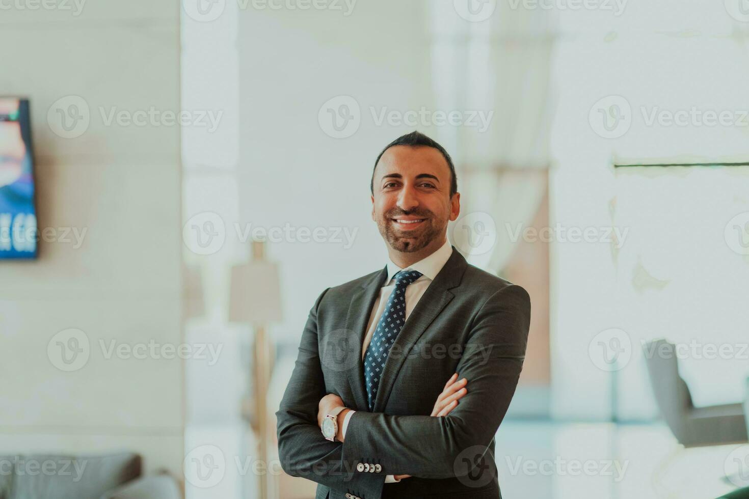 retrato do uma homem de negocios dentro uma terno com dele braços cruzado dentro uma moderno escritório construção foto