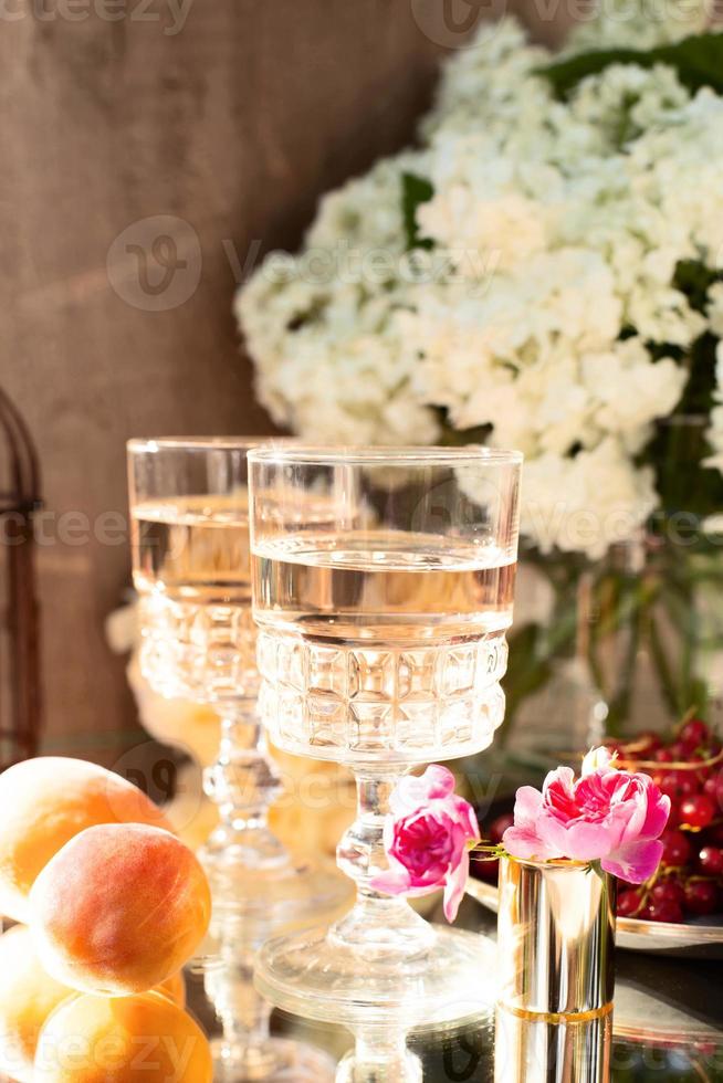 vinho rosado em taças em garrafas douradas com flores e frutas foto