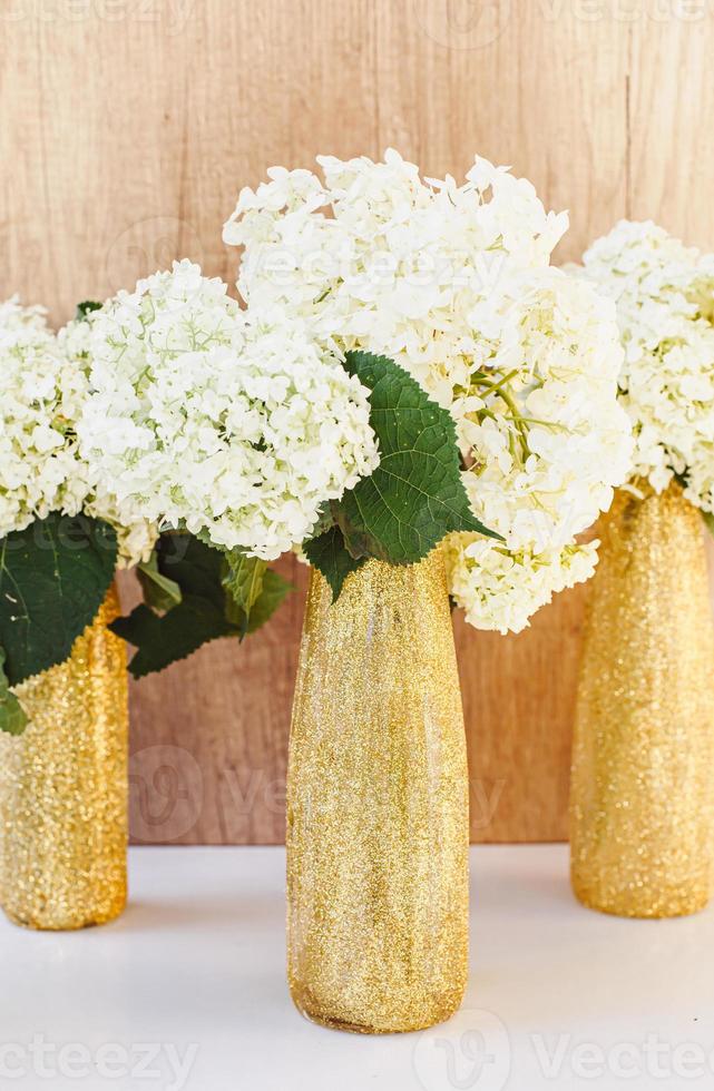 frascos de ouro cintilante com flores de hortênsia. vasos de ouro foto