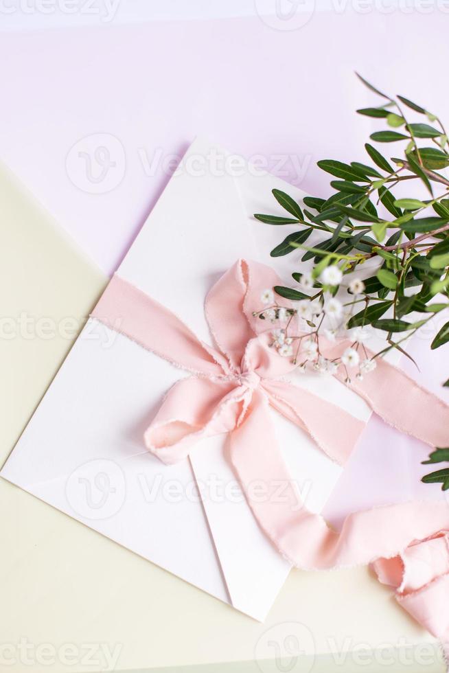 envelope em um fundo branco-rosa com fita de seda cor de pêssego foto