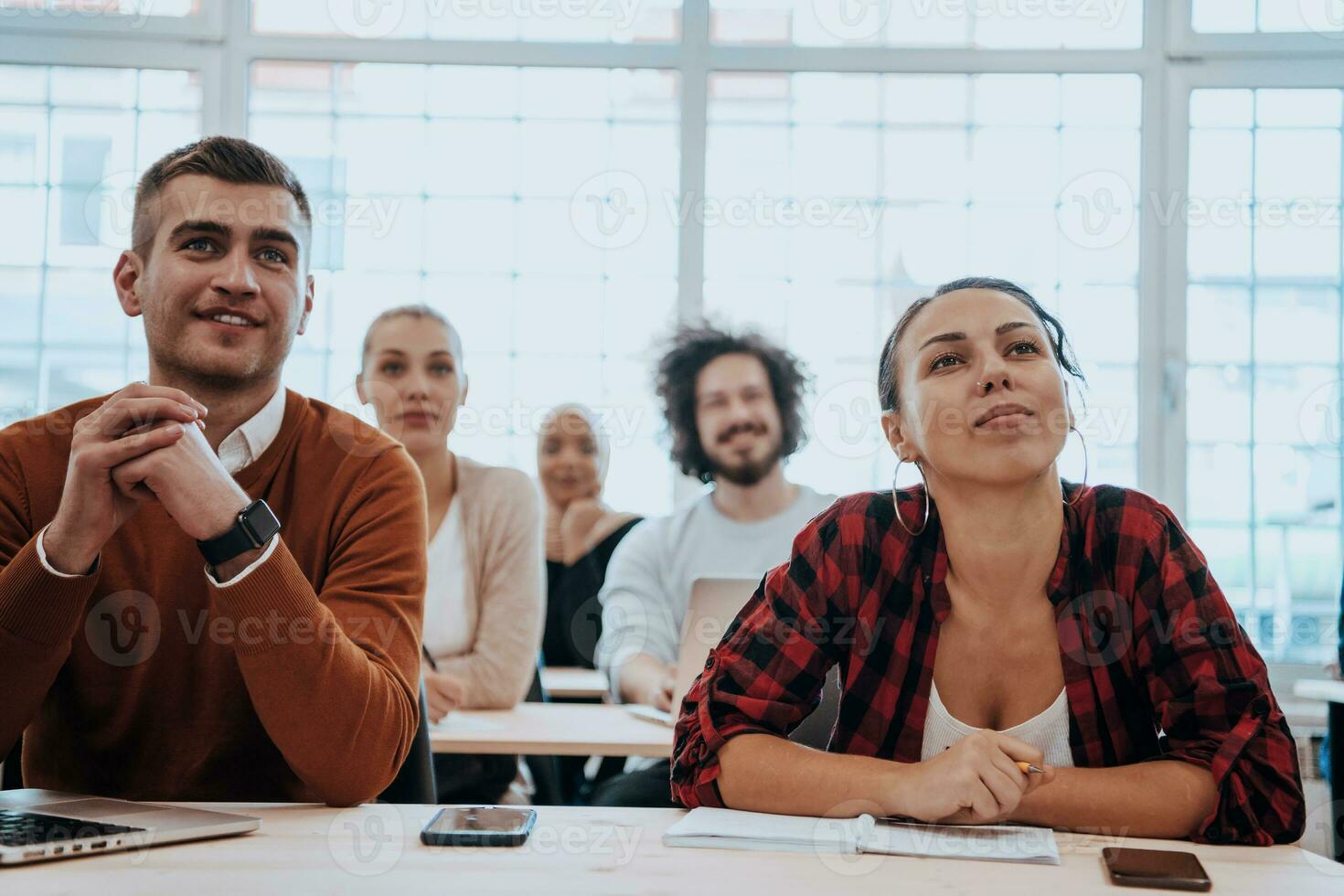 uma grupo do diverso jovem homens e mulheres sentar dentro uma moderno Sala de aula e ouço para uma palestra em o negócio Treinamento foto