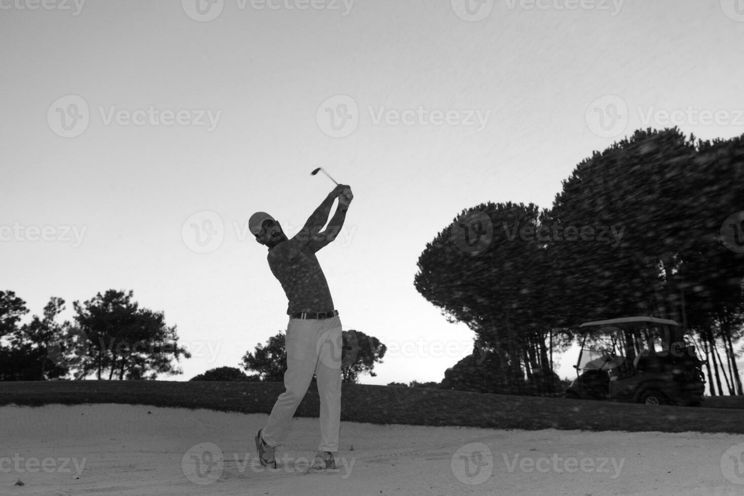 golfista acertando um bunker de areia no pôr do sol foto