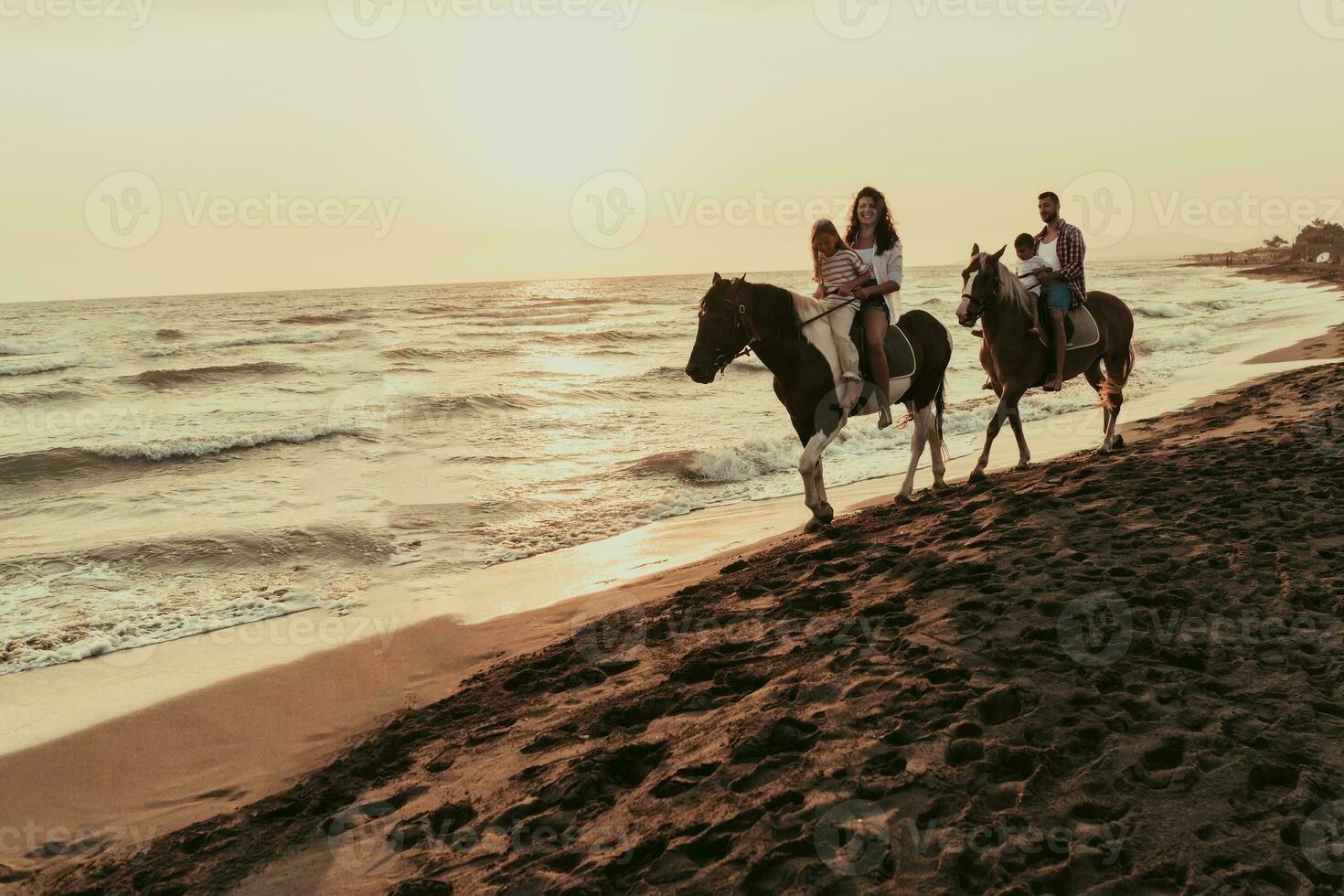 a família passa o tempo com seus filhos enquanto andam a cavalo juntos em uma praia de areia. foco seletivo foto