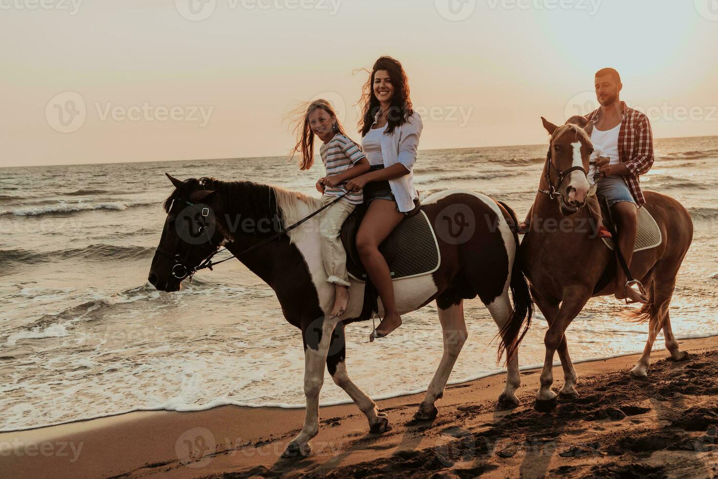 a família passa o tempo com seus filhos enquanto andam a cavalo juntos em uma praia de areia. foco seletivo foto