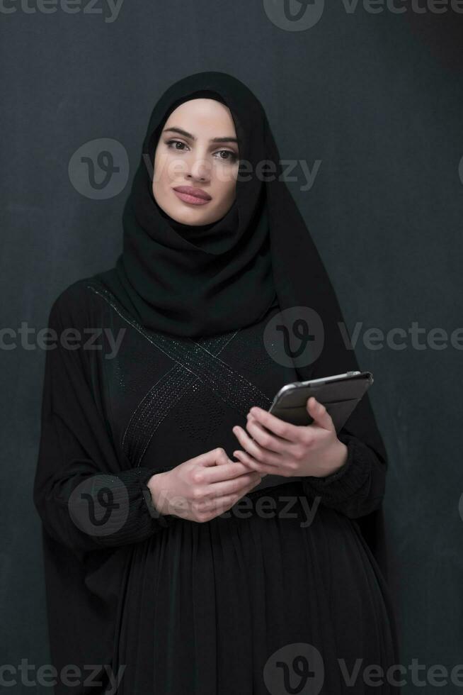 jovem moderno muçulmano o negócio mulher usando Smartphone vestindo hijab roupas dentro frente do Preto quadro-negro foto