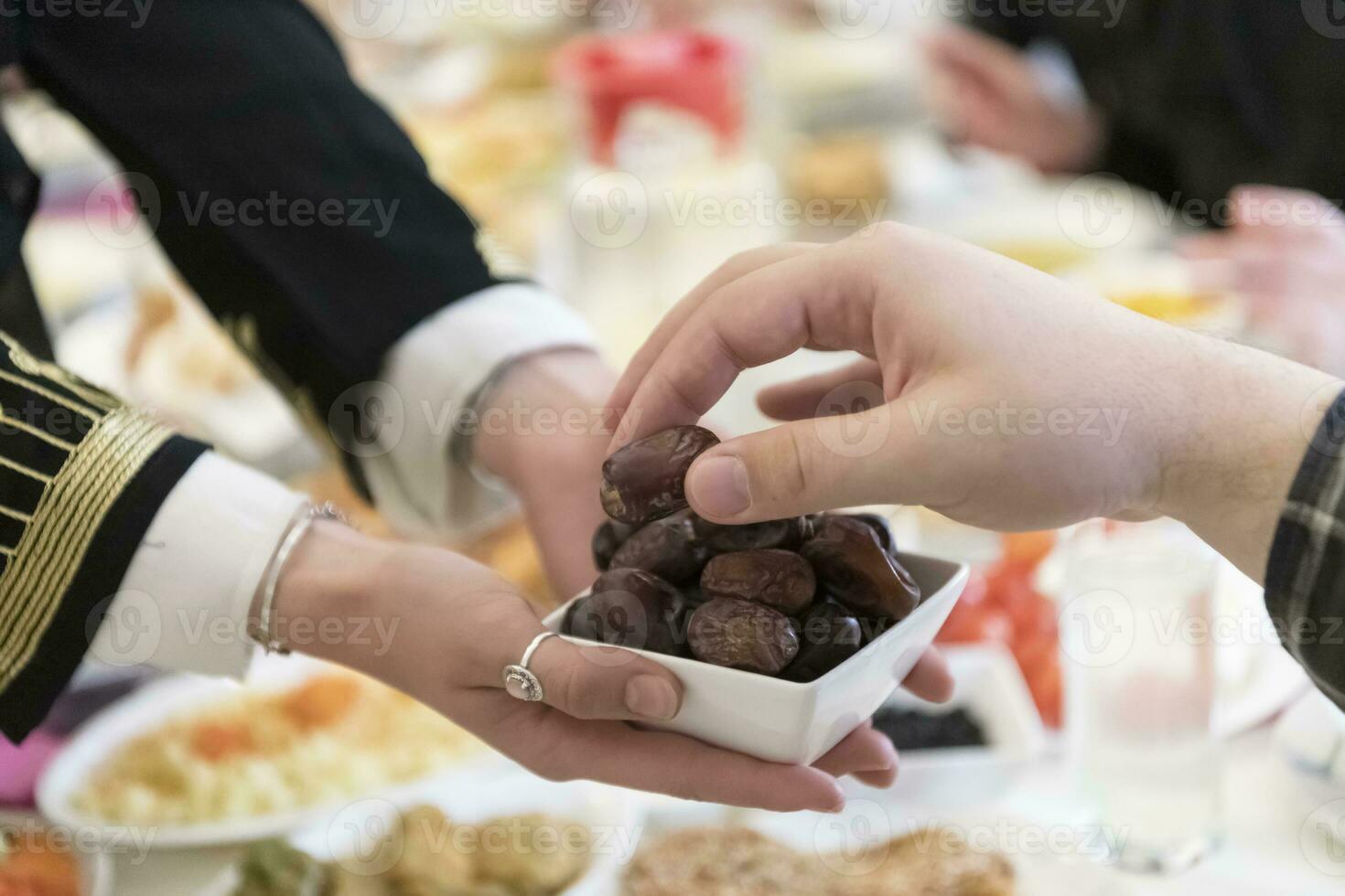 moderno multiétnico muçulmano família partilha uma tigela do datas enquanto desfrutando iftar jantar juntos durante uma Ramadã festa às casa foto