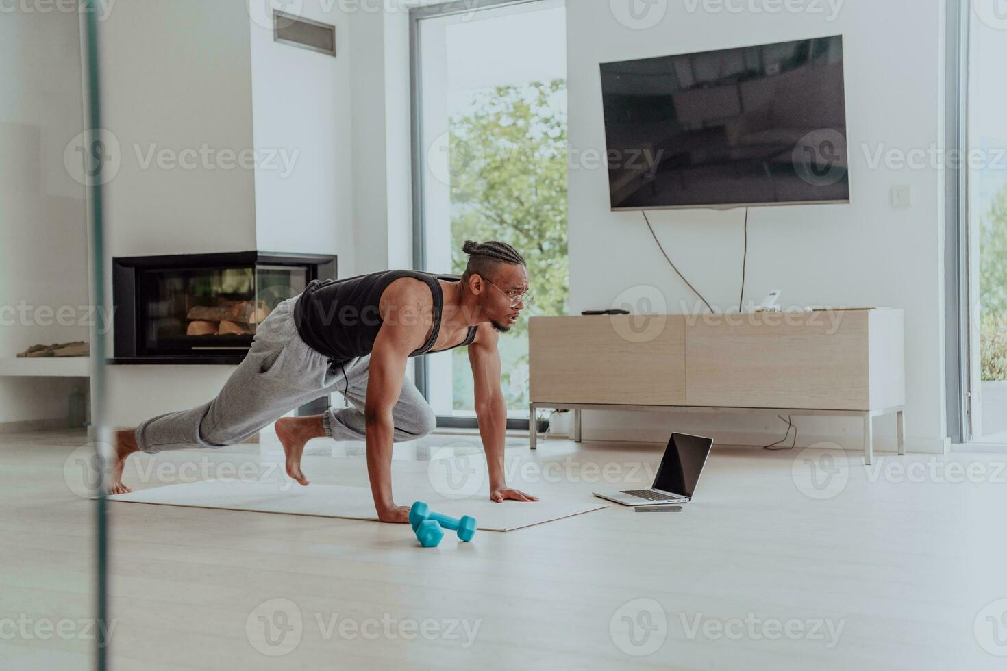 Treinamento às lar. desportivo homem fazendo Treinamento enquanto assistindo conectados tutorial em computador portátil, exercício dentro vivo sala, livre espaço foto