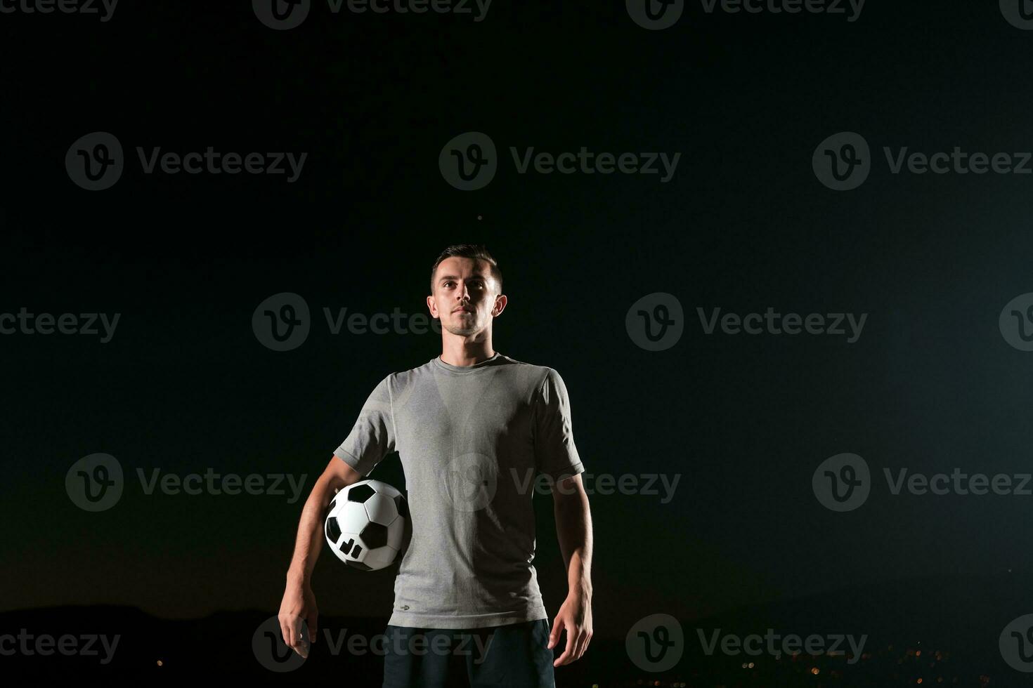 retrato do uma jovem bonito futebol jogador homem em uma rua jogando com uma futebol bola. foto