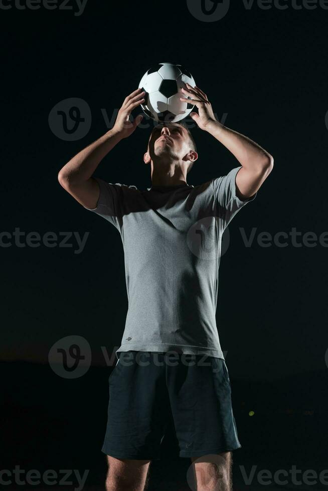 retrato do uma jovem bonito futebol jogador homem em uma rua jogando com uma futebol bola. foto