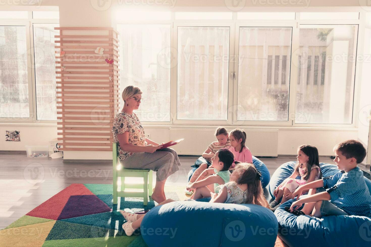 lendo Tempo dentro elementar escola ou Jardim da infância, professor lendo uma livro para crianças dentro elementar escola ou jardim de infância. seletivo foco foto