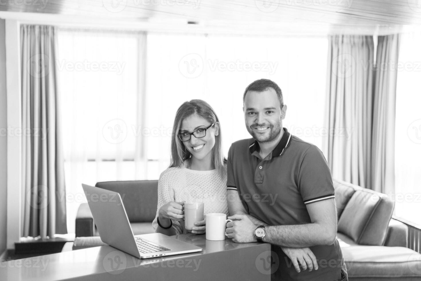 casal tomando café e usando laptop em casa foto