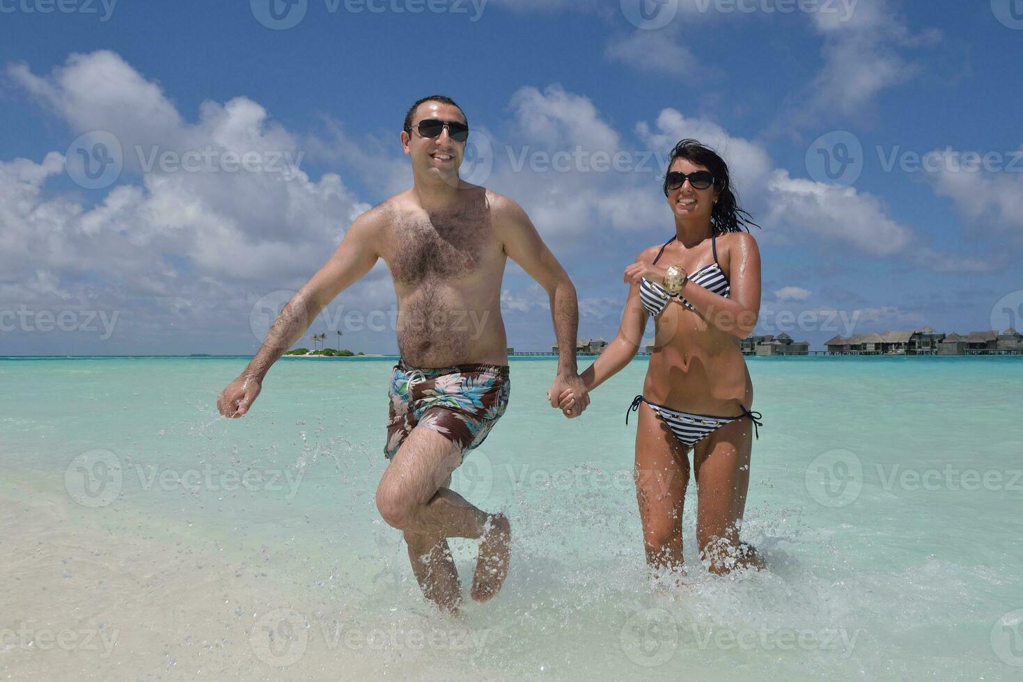 feliz casal jovem se divertir na praia foto