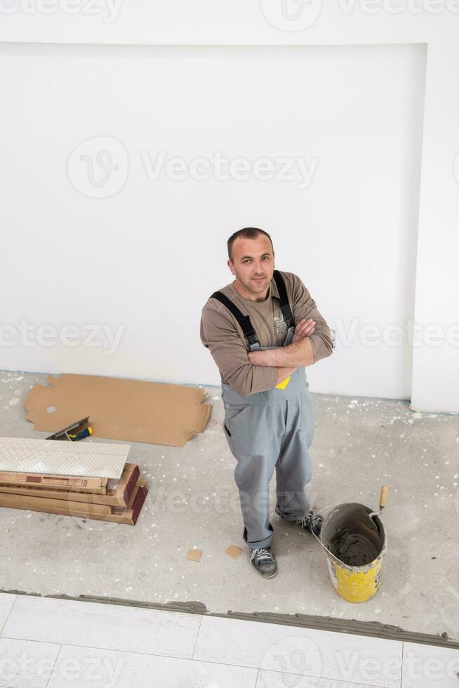 trabalhador instalando as telhas cerâmicas de efeito de madeira no chão foto