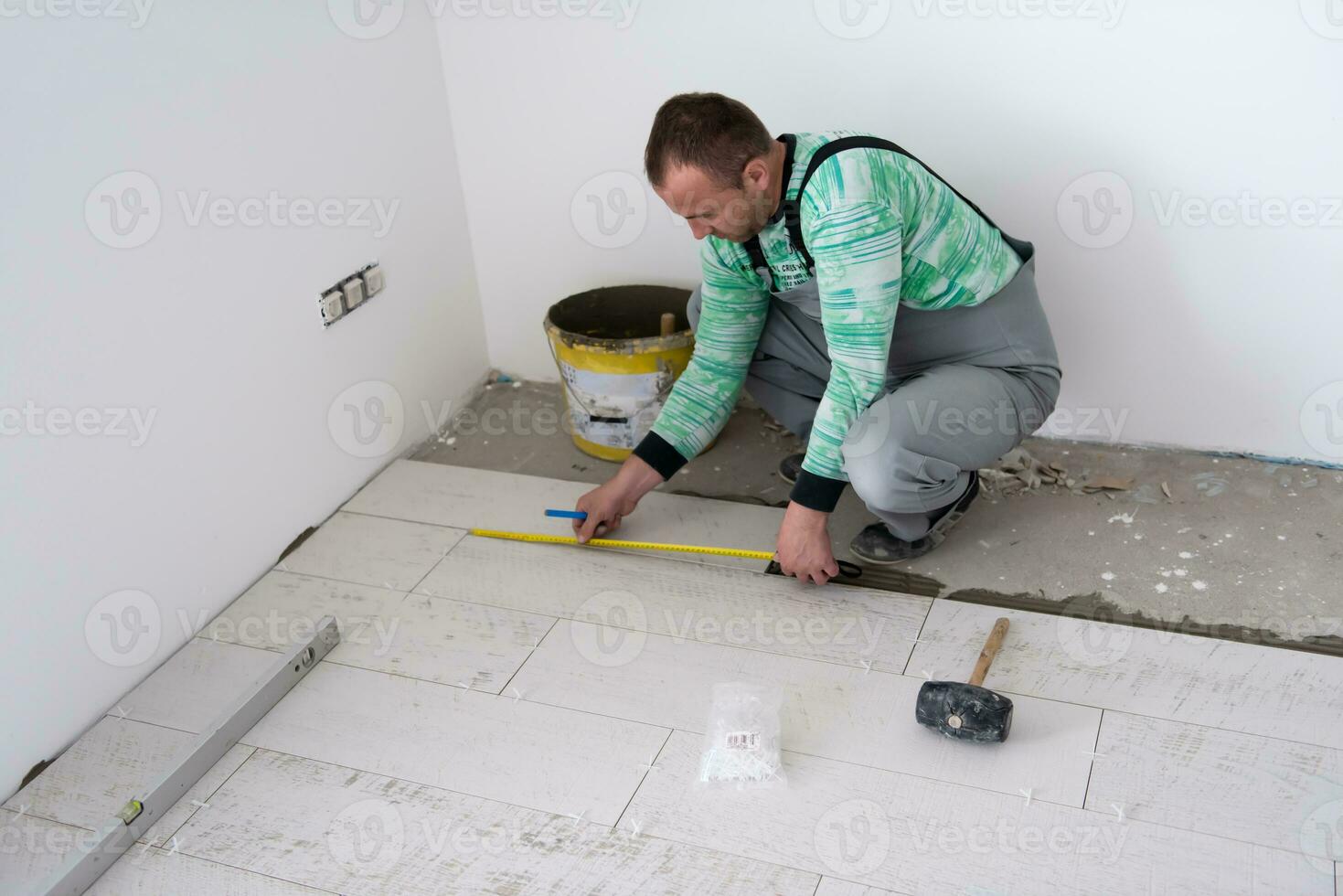 trabalhador instalando as telhas cerâmicas de efeito de madeira no chão foto