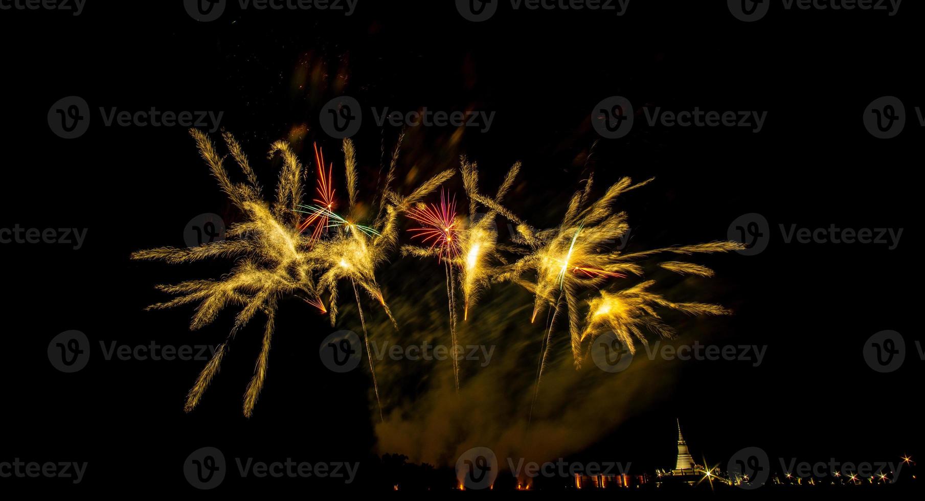 fogos de artifício enormes e coloridos sobre os campos de arroz ao entardecer. foto