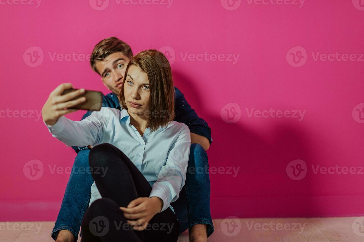 um jovem casal feliz sentado no chão em casa e fazendo selfie foto
