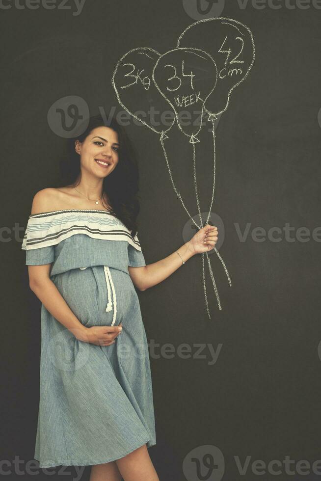 retrato de mulher grávida na frente de lousa preta foto