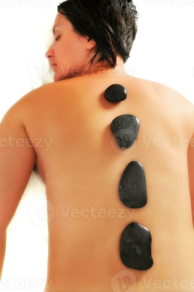 mulher bonita tem massagem hotstone no spa e centro de bem-estar foto