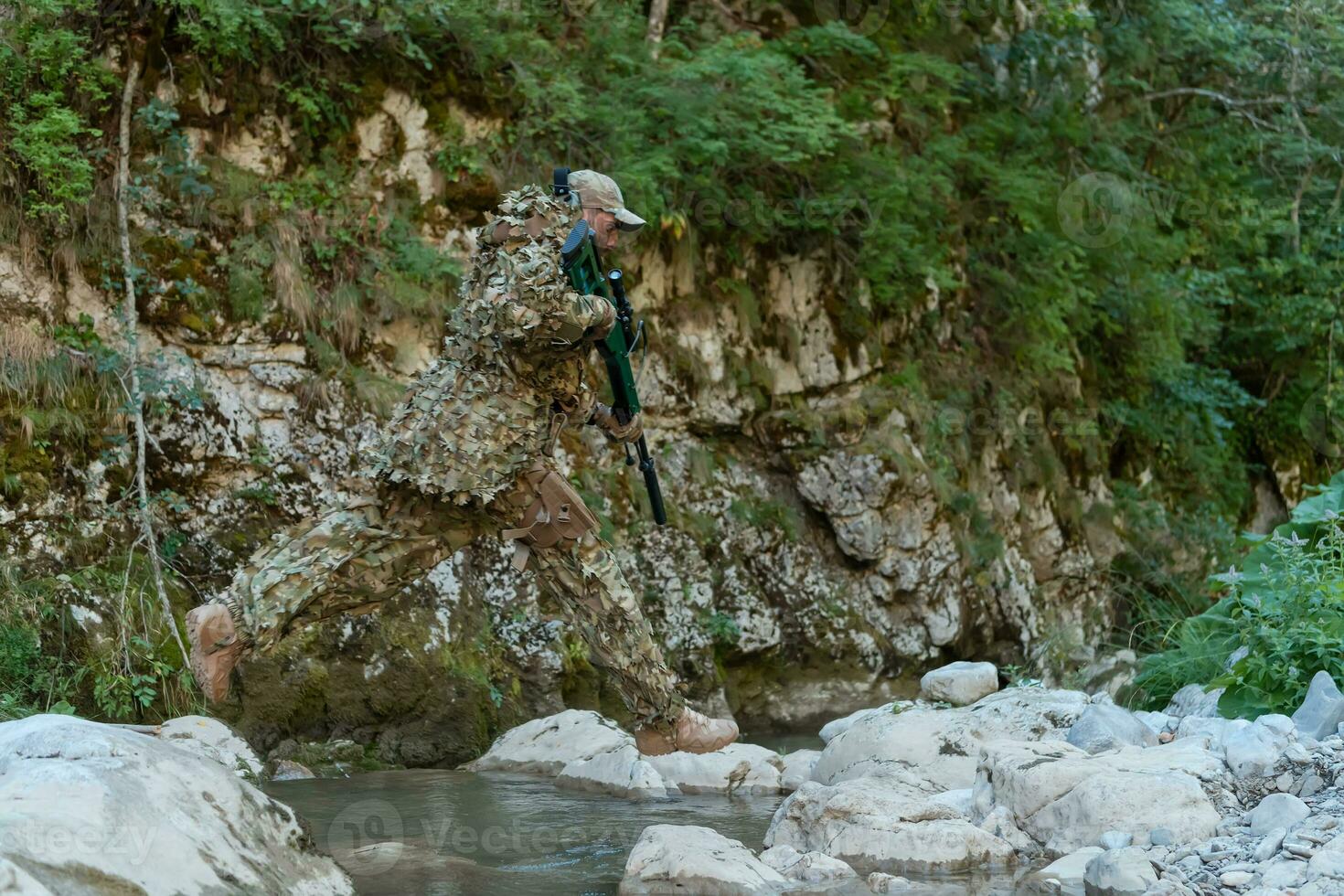 uma militares homem ou airsoft jogador dentro uma camuflar terno esgueirar-se a rio e mira a partir de uma Franco atirador rifle para a lado ou para alvo. foto