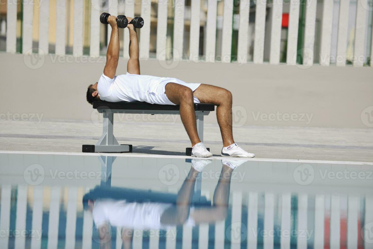 jovem homem exercício às à beira da piscina foto