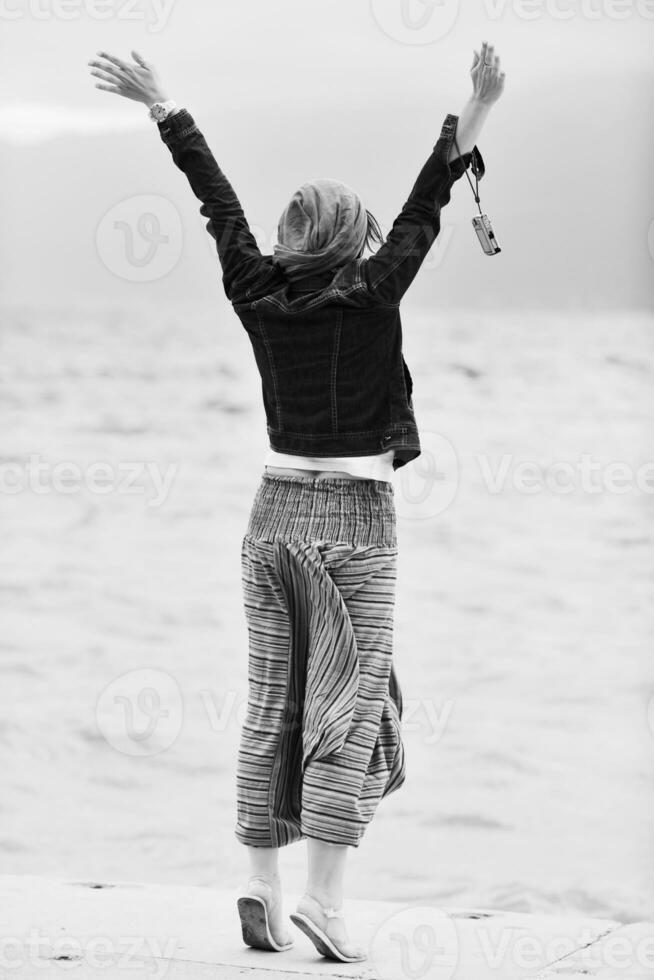 mulher jovem e bonita na praia com cachecol foto